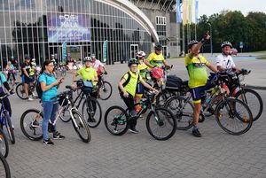 Grupa rowerzystów przed halą widowiskowo-sportową