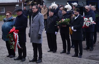 Osoby ustawione w szeregach do złożenia kwiatów, wsród nich osoby w galowych mundurach górniczych