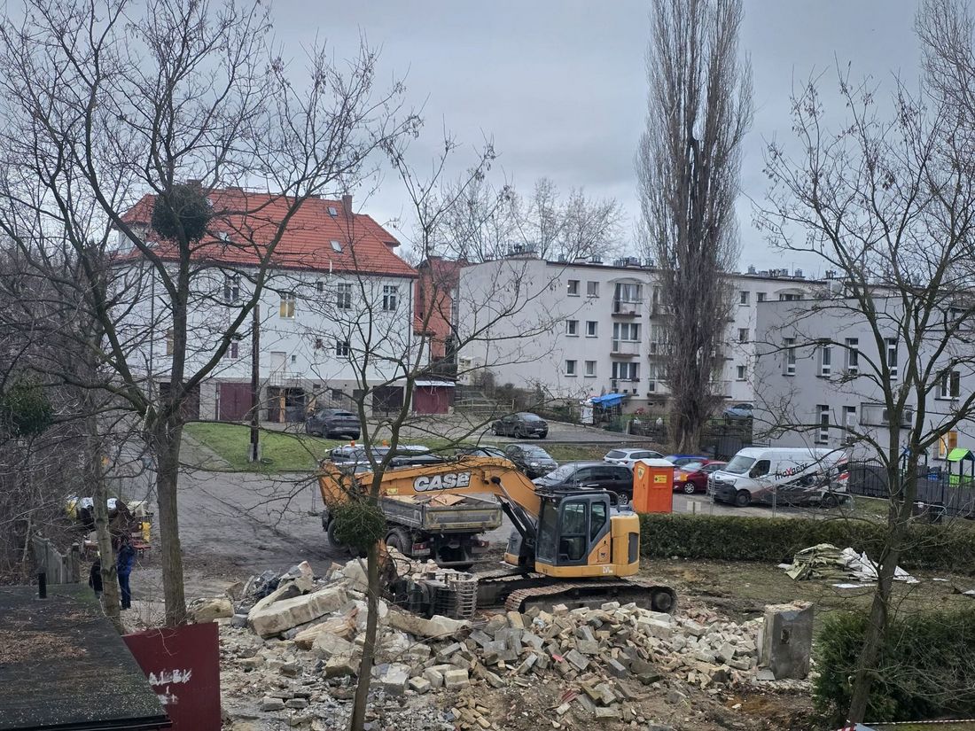 widok na prace budowlane przy rozbiórce budynku - dżwig, przed nim gruz