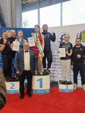 Zawodnczki stojące na stopniach podium, trenerzy oraz uczestnicy wydarzenia