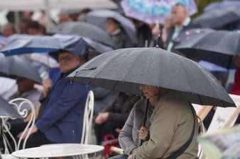 Publiczność siedząca przed scena pokryta parasolami