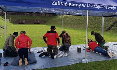 strzelający do tarcz ludzie pod wiatą w pozycji leżącej