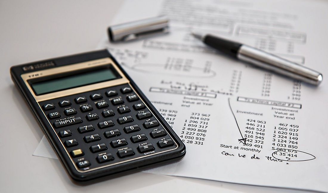 Zdjęcie przedstawia zastawienie finansowe obok którego leży kalkulator oraz pióro