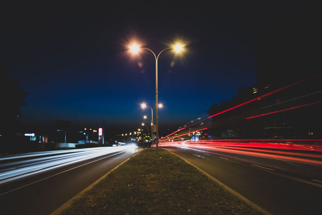 Miasto nocą - świecąca latarnia i rozmazane światła samochodów