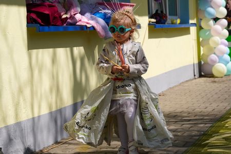 Dziewczynka w okularach przeciwsłonecznych w sukni z materiałów z recyklingu