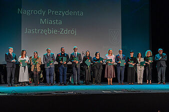 Prezydent Michał Urgoł i drug zastęca prezydenta miasta Andrzej Matusiak wraz z nagrodzonymi nauczycielami stoją na scenie w kinie Centrum podczas uroczystości Dnia Edukacji Narodowej 