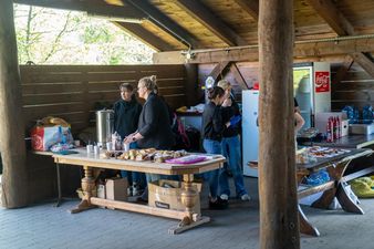 stoisko gastronomiczne ustawione pod wiatą przy nim obsługują 3 kobiety w czarnych strojach 