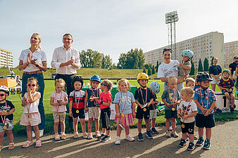 Grupa dzieci z medalami na szyjach stoi do wspólnego zdjęcia w asyście organizatorów i zaproszonych gości