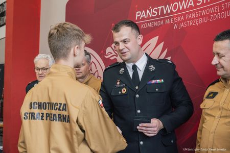 Przekazanie nagrody uczestnikowi w stroju strazackim podczas konkursu w trzeciej grupie