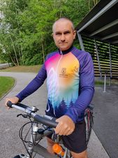 Konrad trzyma kierownice roweru ubrany w koszulkę z długimi fioletowymi rekawami