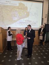 kobieta w czerwonej bluzce otrzymuje podziękowania od Prezydenta Michała Urgoła