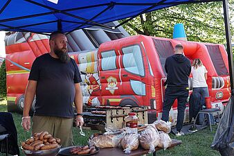pan sprzedaje grilowane kiełbasy w tle dmuchaniec dla dzieci
