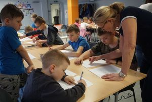 Dzieci biorące udział w feriach z MOSiR-em słuchają poleceń instruktorki