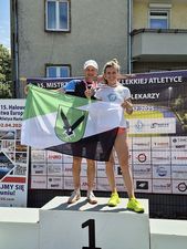 Medaliści TL Athletics na podium z flagą Jastrzębia-Zdroju