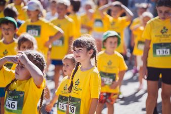 Dziewczynka w żółtej koszulce patrząca przed siebie, w tle więcej dzieci ubranych na żółto