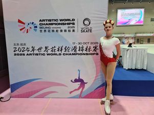 Zawodniczka stojąca przy ściane opisującej w języku angielskim i chińskich rozgrywane mistrzostwa. Ubrana w barwy biało czerwone z wiankiem na głowie również w barwach narodowych