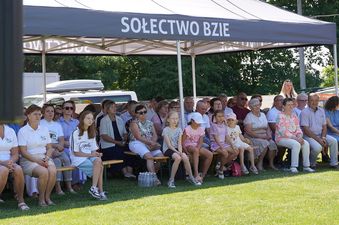 Uczestnicy na ławkach pod namiotem