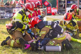 Strażacy pomagają poszkodowanej osobie leżącej na noszach