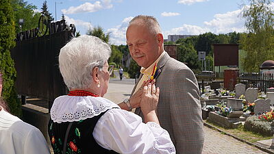 Kobieta przypina mężczyźnie kotylion