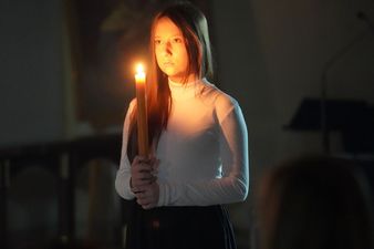 Młoda kobieta trzyma płonącą świecę