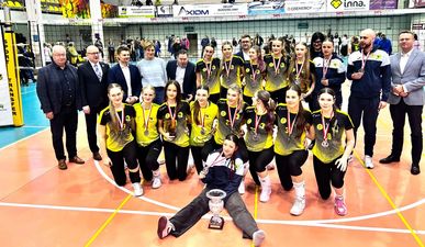 Grupowe zdjęcie drużyny JKS-u z medalami i pucharem w dwóch rzędach - jeden kleczący na jednym kolanie, drugi na stojąco. Obok działacze