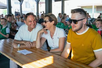 Grupa dorosłych uczestników festynu, w tym goście, rozmawiających przy stole pod zadaszoną wiatą