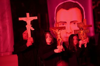 Aktorzy trzymający w rękach krzyże, w tle wizerunek księdza Jana Machy