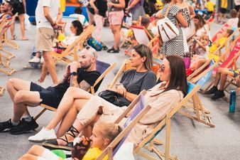 Grupa dorosłych oraz dzieci siedzących na leżakach