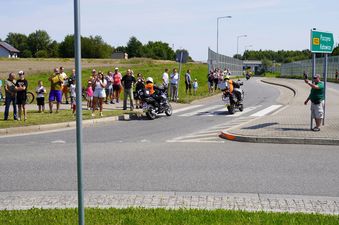 Dwa motocykle podczas przejazdu przez rondo, wookół kibice