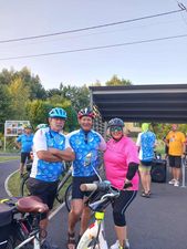 Trójka ludzi stoi obok siebie pozując do zdjęcia przy swoich rowerach