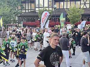 Tłum ludzi na plenerowym pikniku rodzinnym. Na pierwszym planie młody mężczyzna w czarnej koszulce