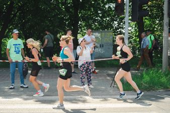 trzy zawodniczki biegną kibice stoją przy trasie 