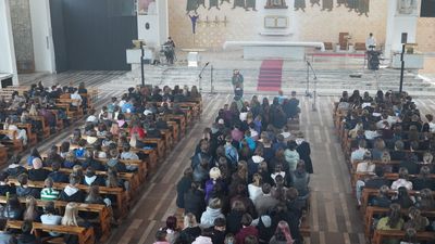 Kościół w środku widziany z góry chóru, widok na siedzącą młodzież i prowadzącego