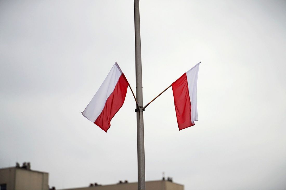 Dwie biało-czerwone flagi Polski umieszczone na słupie 