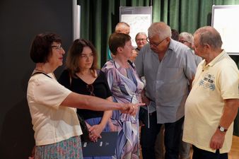 Grupa ludzi ogląda obrazy, jedna kobieta wskazuje na szczegół
