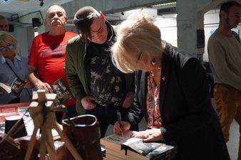 8. Eleonora Szafran podpisuje swoją książkę „Mistrz” podpisująca książkę, obok uczestnicy spotkania 