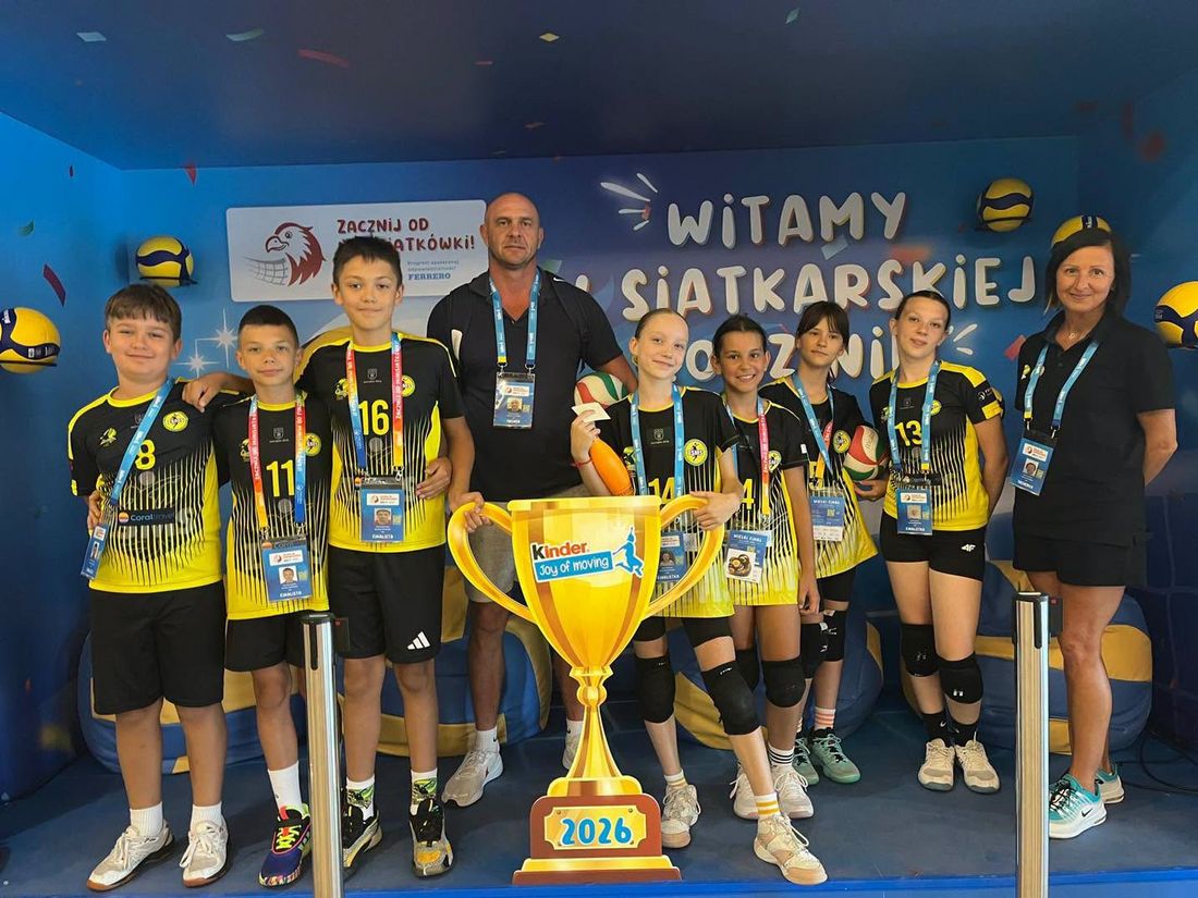 Drużyna z trenerami i makietą pucharu na niebieskim tle