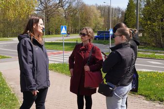 Trzy kobiet rozmawiające, stojące na chodniku.