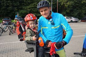 Rowerzysta z małym dzieckiem przed halą widowiskowo-sportową