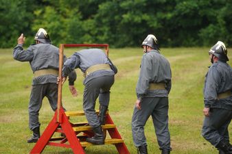 Czterech członków OSP Rogów pokonujących w wolnym tempie tor przeszkód - przejście pod poręczą 