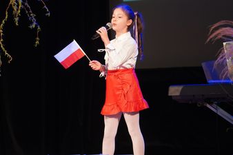 Piosenkarka w biało czerwonym stroju wymachująca polską flagą