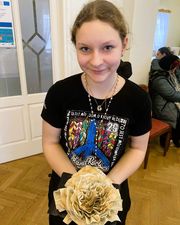 Dziewczynka trzymająca w rękach pracę z gazety w kształcie kawiatka