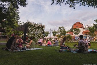 uczestnicy siedzą na kocykach i plotą wianki 