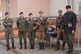 Grupa osób w strojach wojskowych, mężczyźni trzymają broń