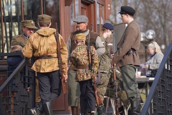 Młodzież oraz dorośli uczestniczący w grze terenowej, na ramionach mają przewieszoną broń