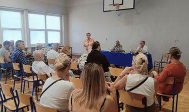 Mieszkańcy Osiedla Zdrój siedzący na krzesłach na sali gimnastycznej ujęcie z tyłu