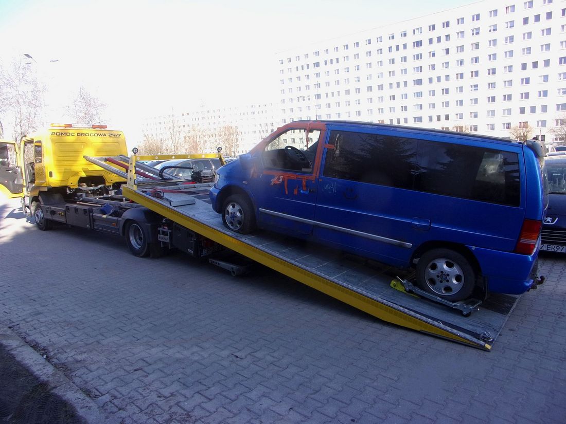 Niebieski wrak samochodu dostawczego wciągany na lawetę