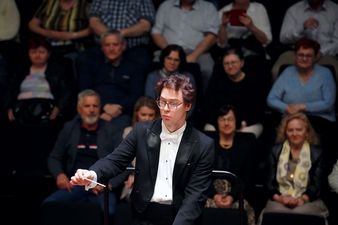 Dyrygent z batutą w tle publiczność