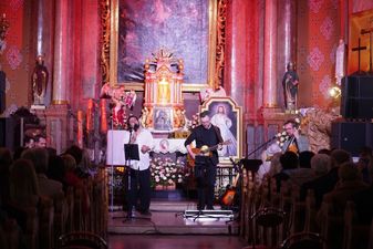 Wokaliosta i gitarzysta przed ołtarzem w kościele w Szerokiej. 