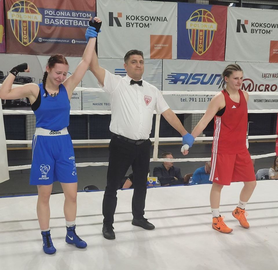 Zawoniczka z podniesioną dłonią przez sędziego, po wygranej walce, obok rywalka.